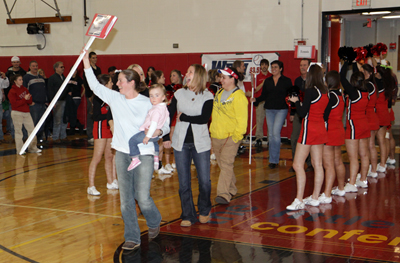 Former Owl player and current women’s assistant soccer coach Sarah Testo, carrying daughter Madison, leads the athletic alums into Spaulding Gym.