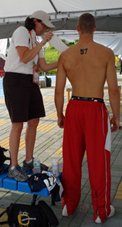 Dr. Wanda Swiger stands on a bench to tape a 6’6” tall athlete at Deaflympics. (Courtesy photo)