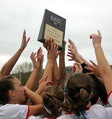 KSC Women's lacrosse team hoists their LEC championship trophy.