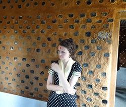 Rose Lovett in front of an earthquake-resistant house made from glass bottles