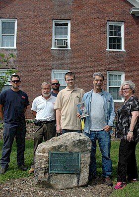 At the monument to Nathan Blake, on the Main Street side of Blake House (l–r): grounds staff Noah Washburn, Bud Winsor, and Joe Britton; Tuck Abert; Ernie Hebert ’69 (with a copy of "The Old American"); and Nancy Howard, regent of the Ashuelot DAR