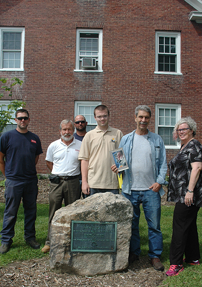 At the monument to Nathan Blake, on the Main Street side of Blake House (l–r): grounds staff Noah Washburn, Bud Winsor, and Joe Britton; Tuck Abert; Ernie Hebert ’69 (with a copy of "The Old American"); and Nancy Howard, regent of the Ashuelot DAR