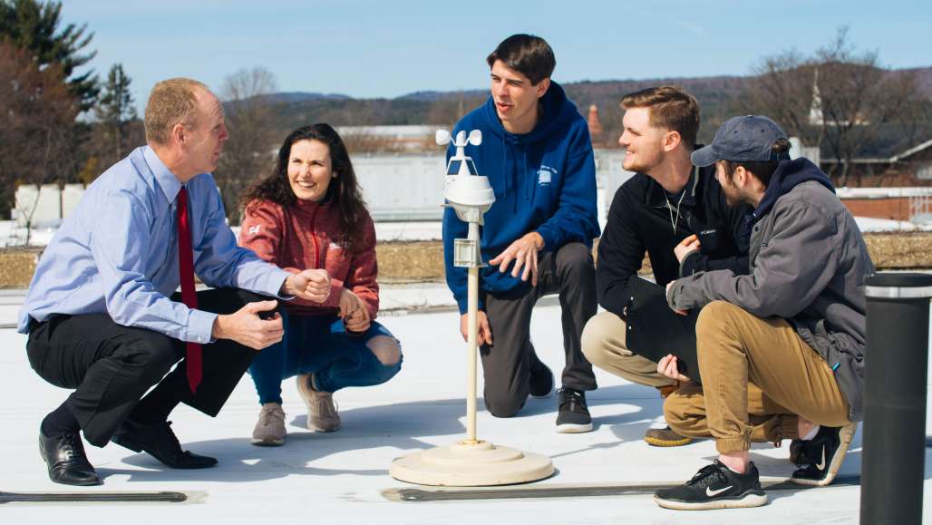 Professor Chris Cusack, left, and his students gather around a weather station on the roof of the Science Center.