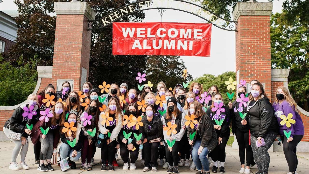 Delta Phi Epsilon members pose for a group photo at the entrance to the Appian Way at KSC