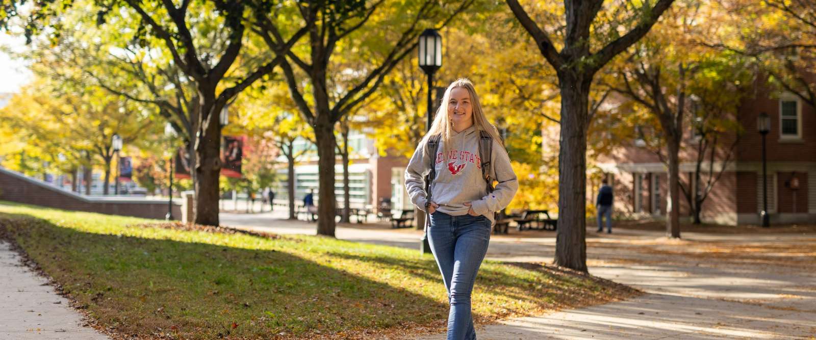 A female student walks across campus in the fall