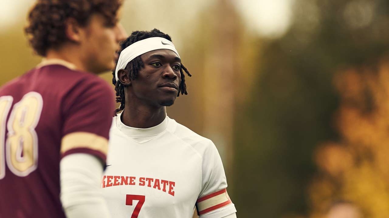 A black male student stands on a soccer field, mid-game