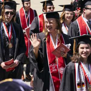 A graduate waves to her family and friends during the procession to Fiske Quad