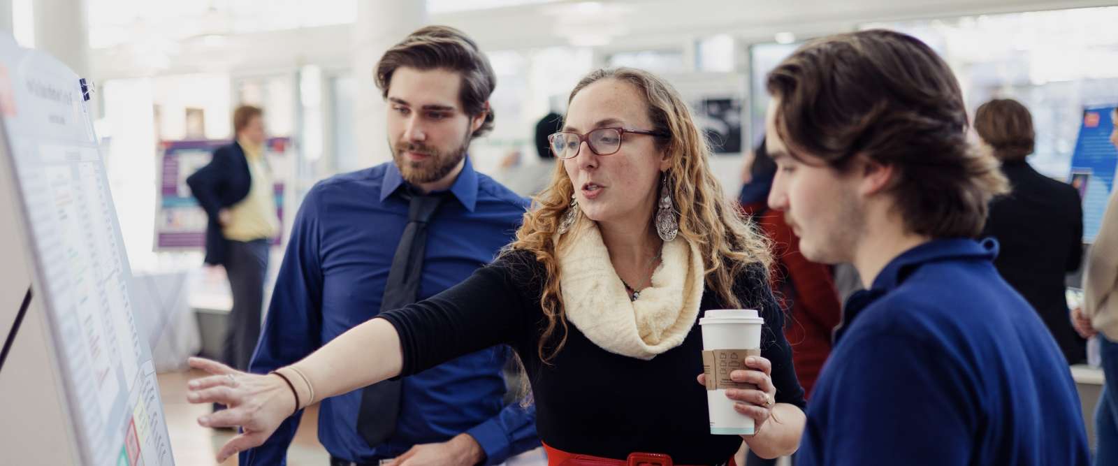 Two students present their poster presentation to a faculty member