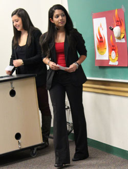 Team members Stacie Coleman (left) and Gabrielle Gentilella present their plan to promote awareness of campus tobacco policy.