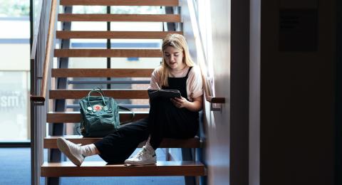 Ashley Rollend sitting on steps working on her iPad