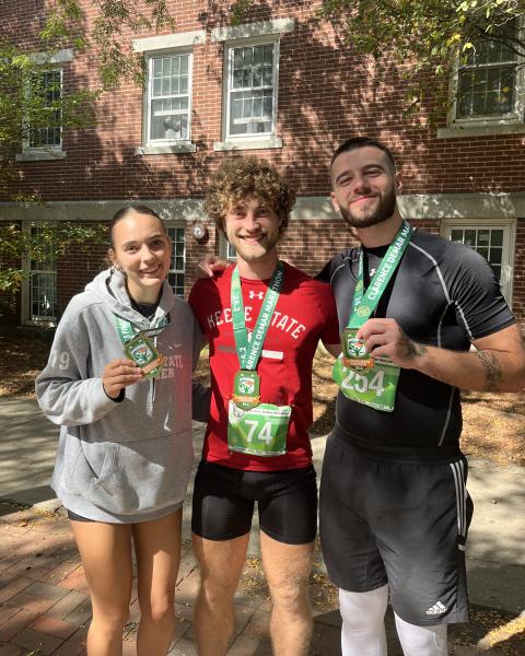 Three students pose together following the running of a marathon holding medals