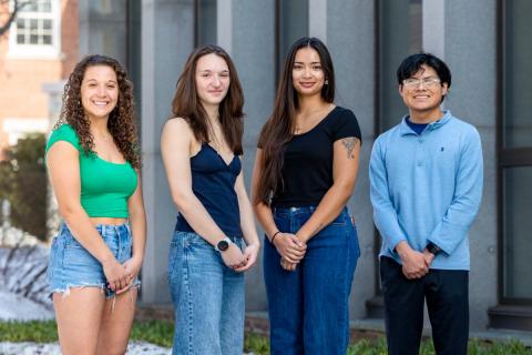 Four students standing in front of building