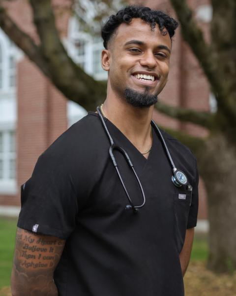 Ali wearing black scrubs and a stethoscope